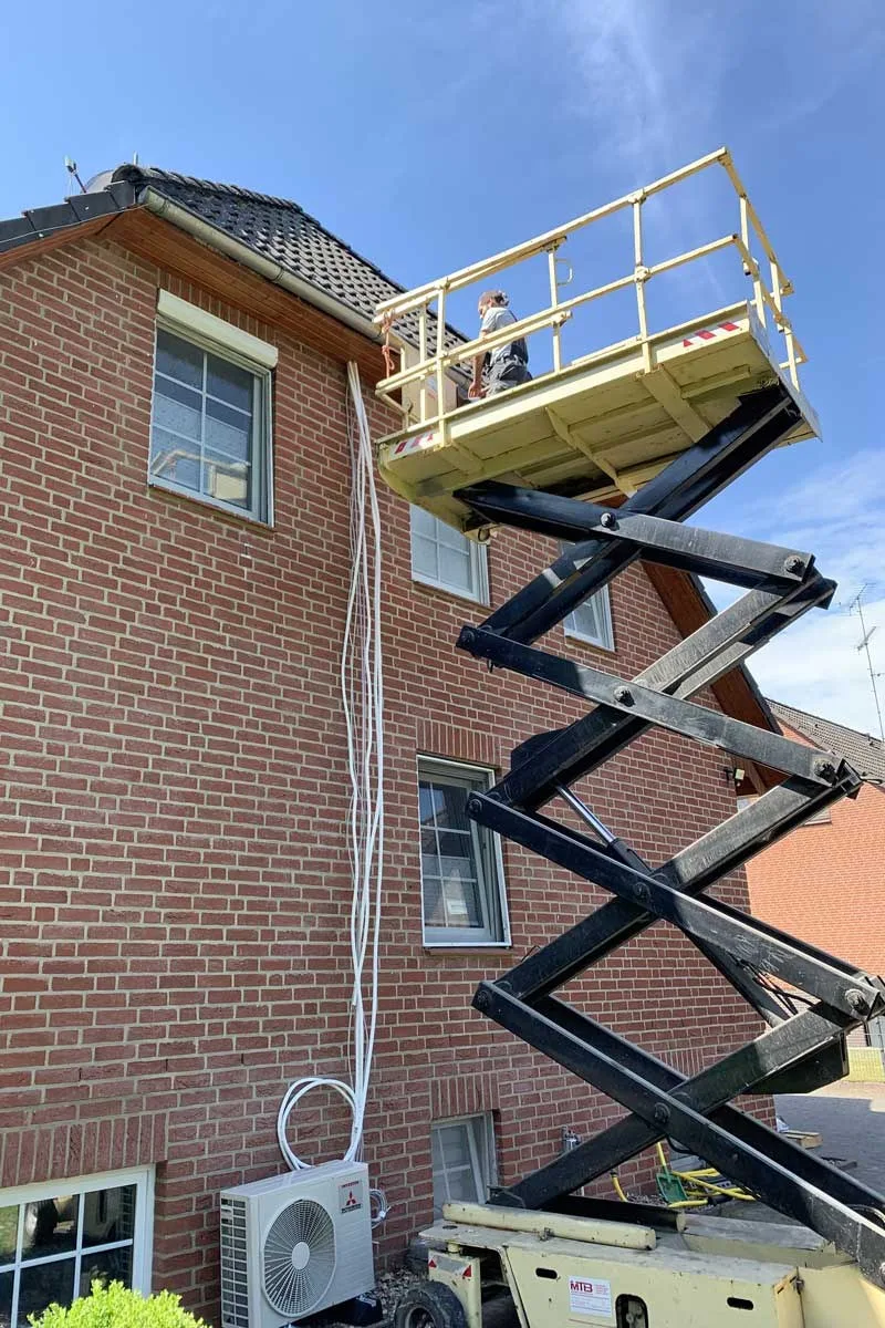 Scherenbühne an einem Backsteinhaus während der Montage einer Klimaanlage