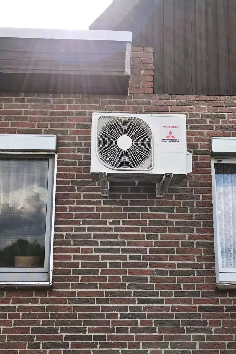 Mitsubishi-Außengerät an einer Backsteinfassade unter dem Fenster