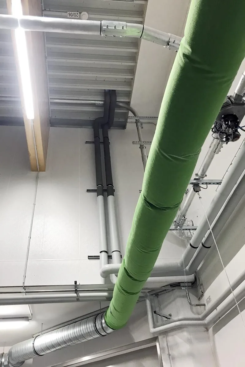 Grün isolierte Kaltwasserleitung unter einer Hallendecke